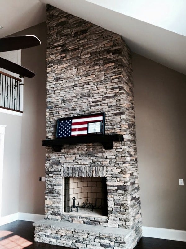 The living area features a high vaulted ceiling and a two-story stone fireplace.