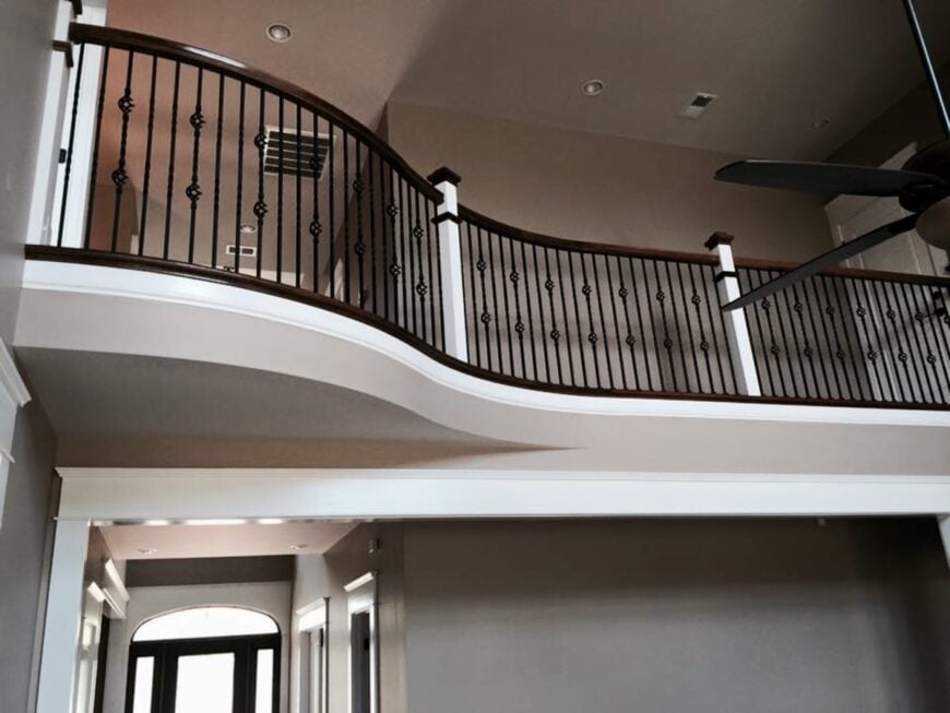 Second-floor balcony with ornate railings overlooking the living room.