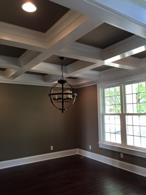 This space is dedicated to the dining room. It has dark hardwood flooring and a coffered ceiling graced with a spherical chandelier.