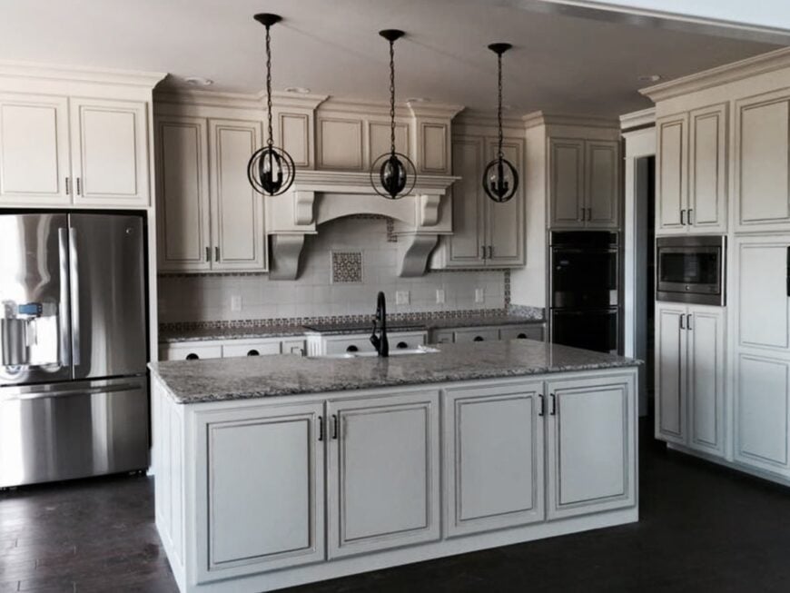 The kitchen is equipped with stainless steel appliances, granite countertops, white cabinetry, and a large prep island.