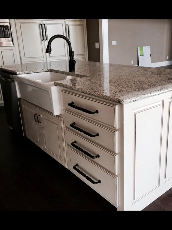 The center island is fitted with a farmhouse sink and a gooseneck faucet.