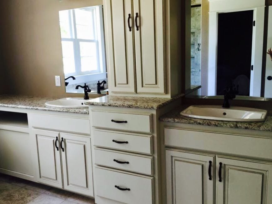 The primary bathroom features a long vanity with his and her sinks, white cabinets, and frameless mirrors.
