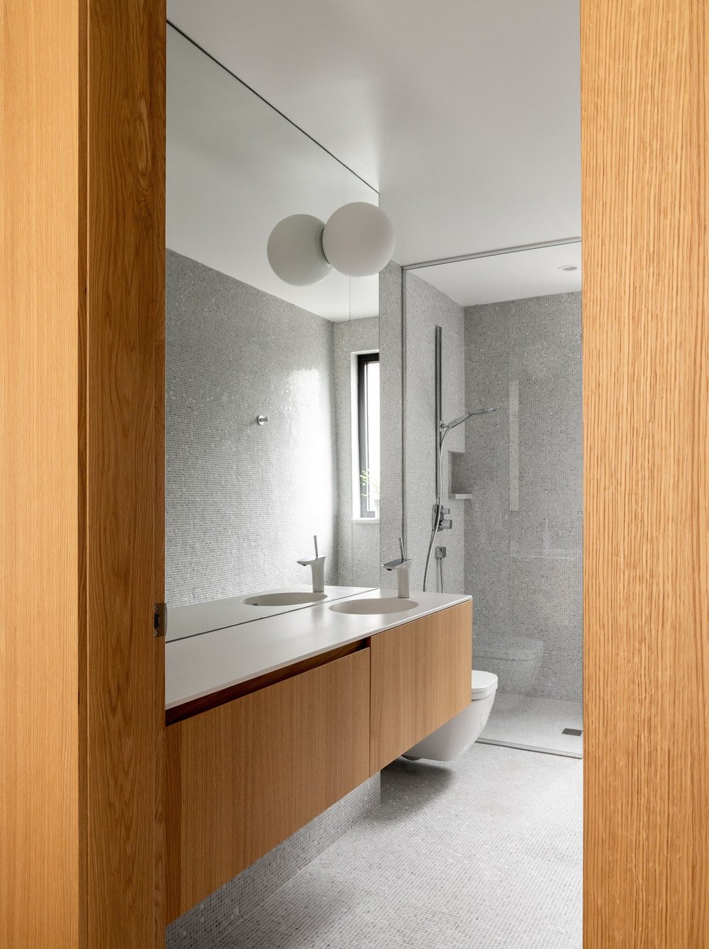 Next to the floating wooden vanity is the toilet, followed by the shower area.