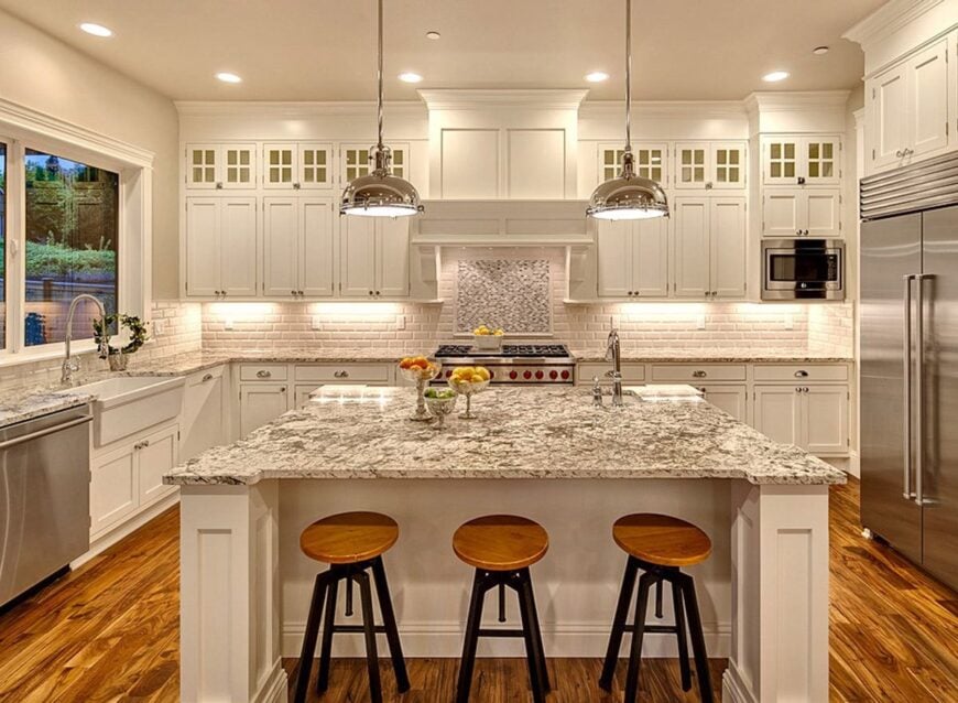 Kitchen with white cabinetry, granite countertops, stainless steel appliances, a farmhouse sink, and a large breakfast island.