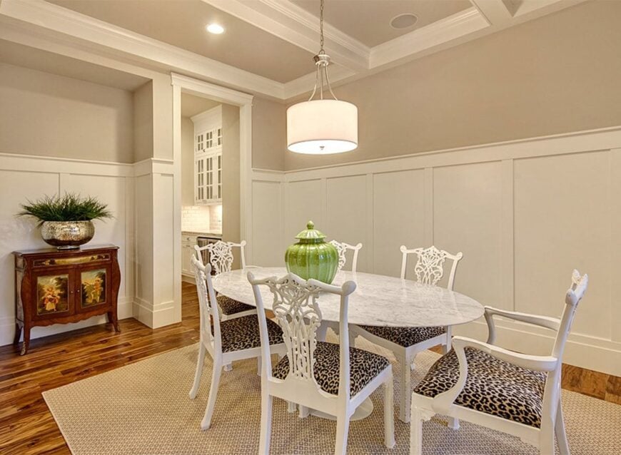 The formal dining room features an oval-shaped marble table paired with leopard cushioned chairs.