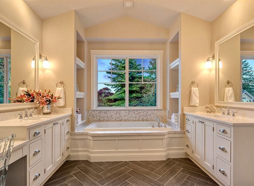 Primary bathroom with his and her vanities, and a deep soaking tub flanked by built-in shelves.