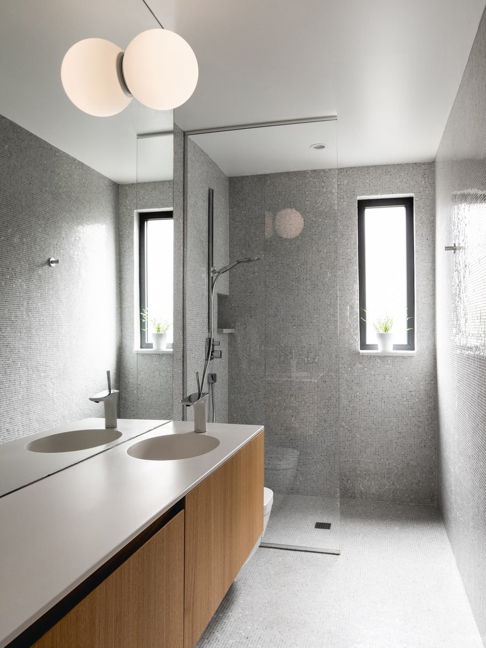 The glass-enclosed shower area has a thin window that brings in natural lighting.