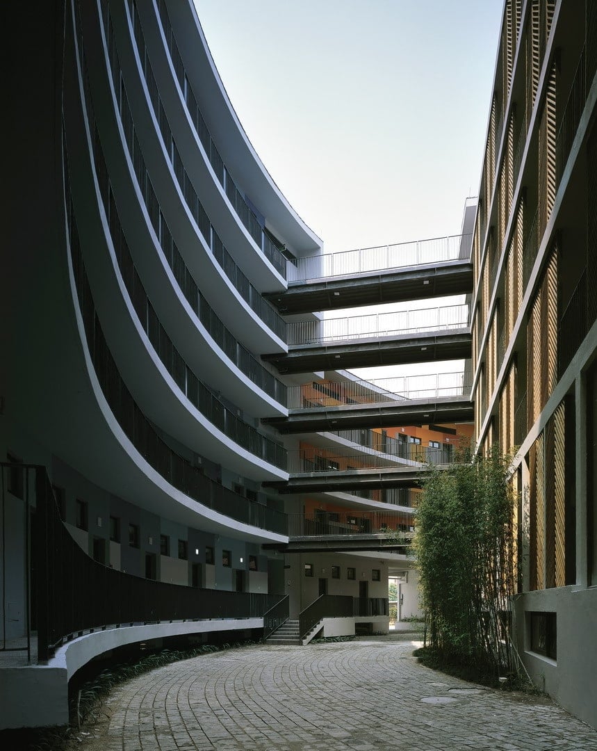 This is a view of the inner courtyard of the large circular building with curved structures, brick walkways and shrub hedges on the side.