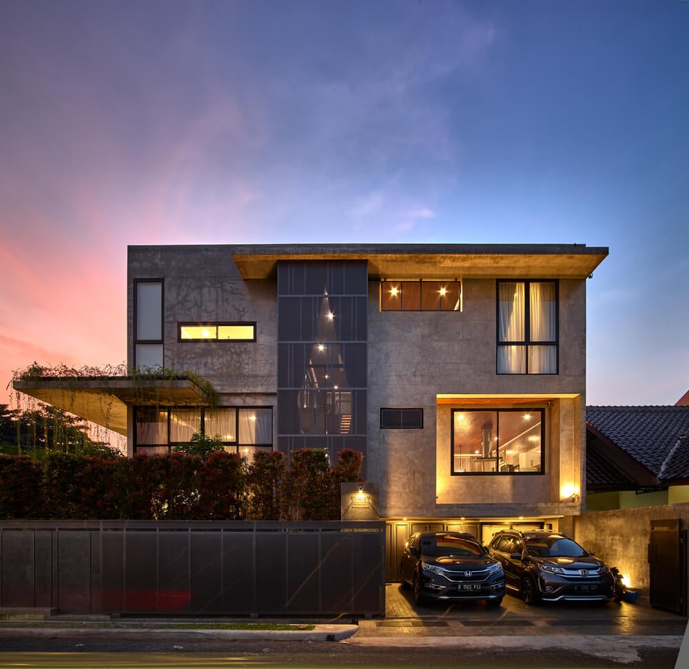 This nighttime view of the front of the house showcases the warm glow of the various windows that pair with the warm outdoor lights of the car port area.