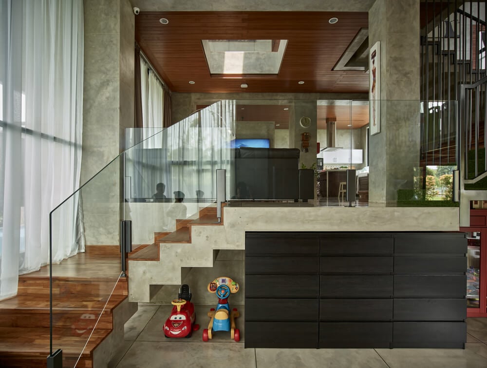 Upon entry, you are welcomed by this foyer that has a large black credenza cabinet next to the glass wall of the staircase that leads to the living room.