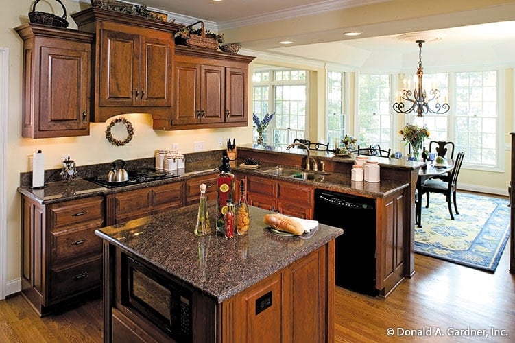 Eat-in kitchen with black appliances, granite countertops, wooden cabinetry, and a small island.