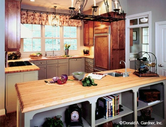 The kitchen offers a prep island, custom cabinetry, wooden countertops, and a wrought iron chandelier.