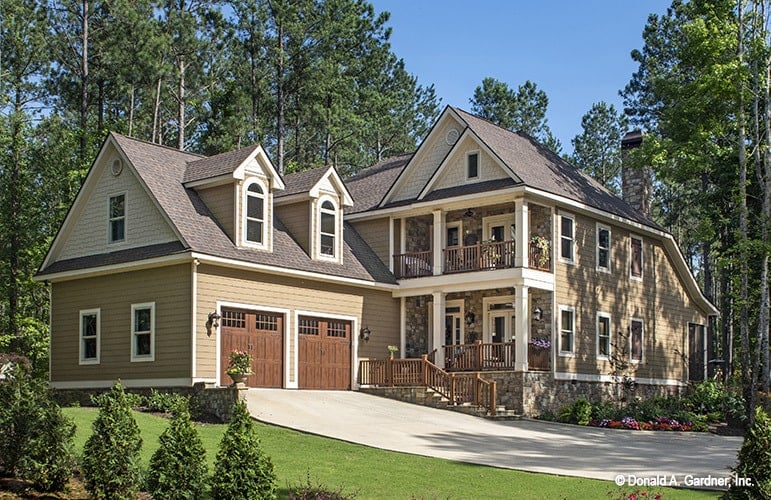 Front exterior view with cedar shake siding, covered porches, and a side-entry garage topped with charming dormers.