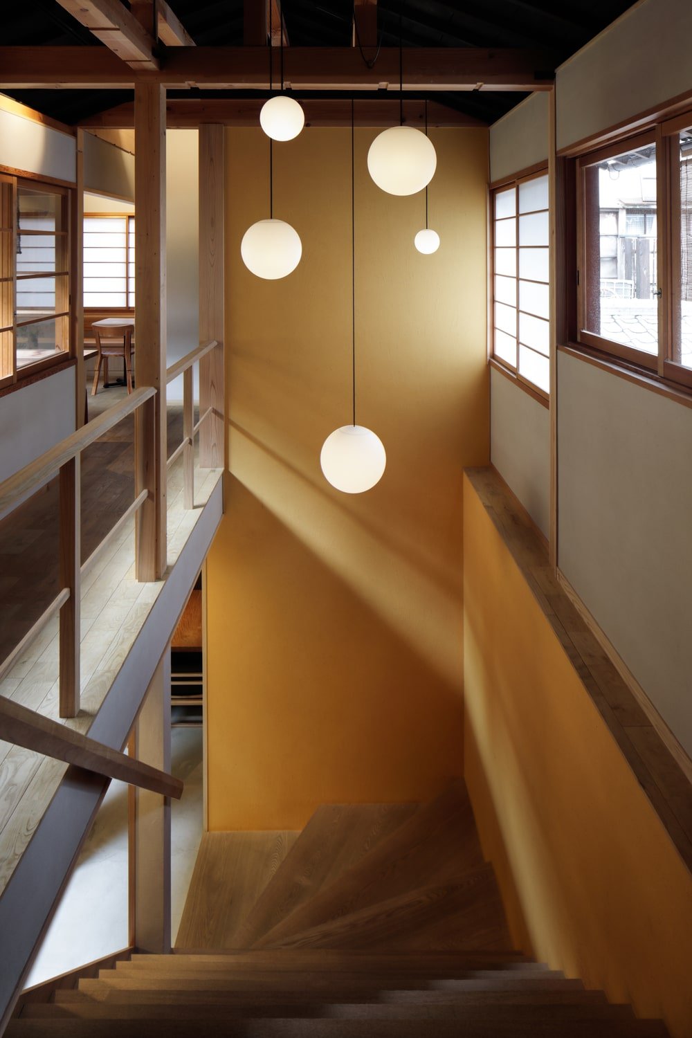 This is a look at the wooden stairs topped with decorative spherical pendant lights hanging above.