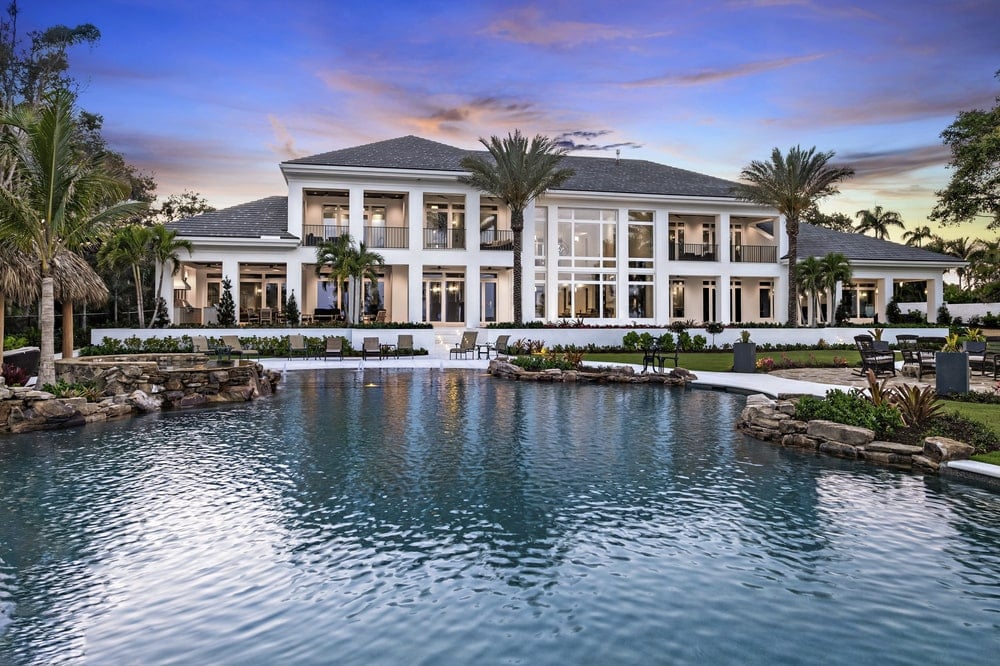 The back of the house has large glass walls, windows and balconies that look over the large pool area of the back of the house.