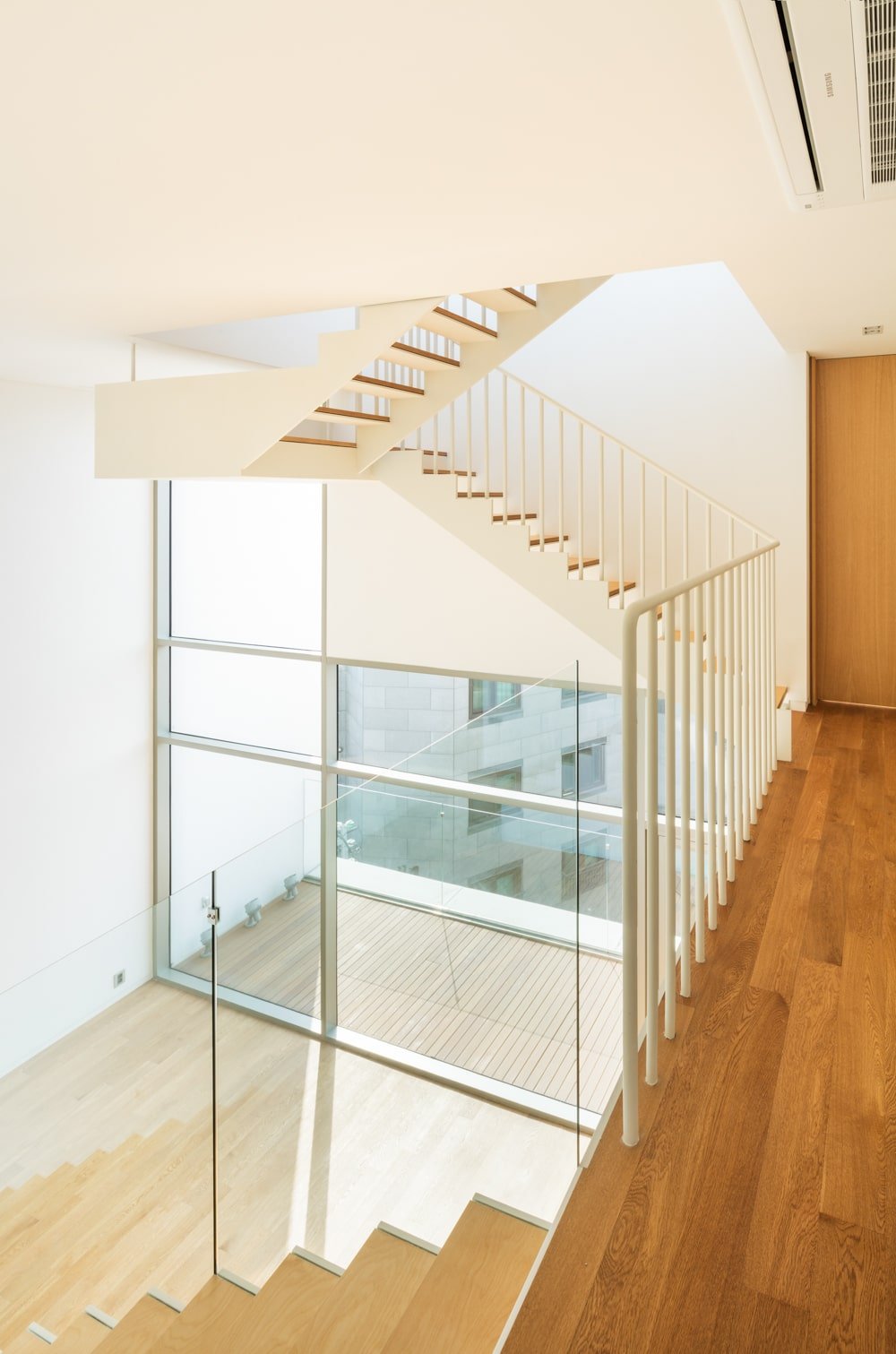 The staircase has a clear view of the floor below due to the glass walls.