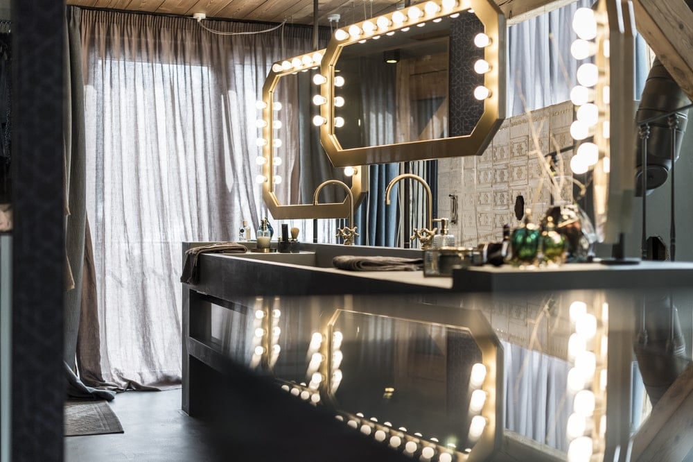 This is a close look at the vanity that is topped iwth a couple of hanging mirrors with warm lights.