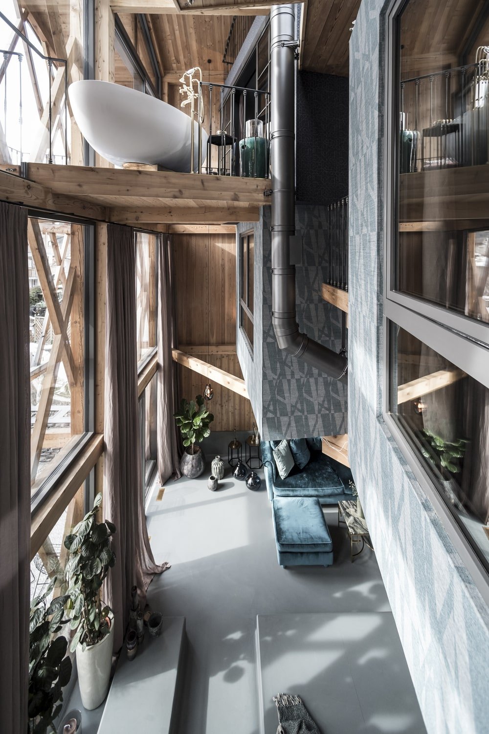 This is a look down on the living room area from the vantage of the indoor balcony showcasing the massive glass wall and wooden accents.