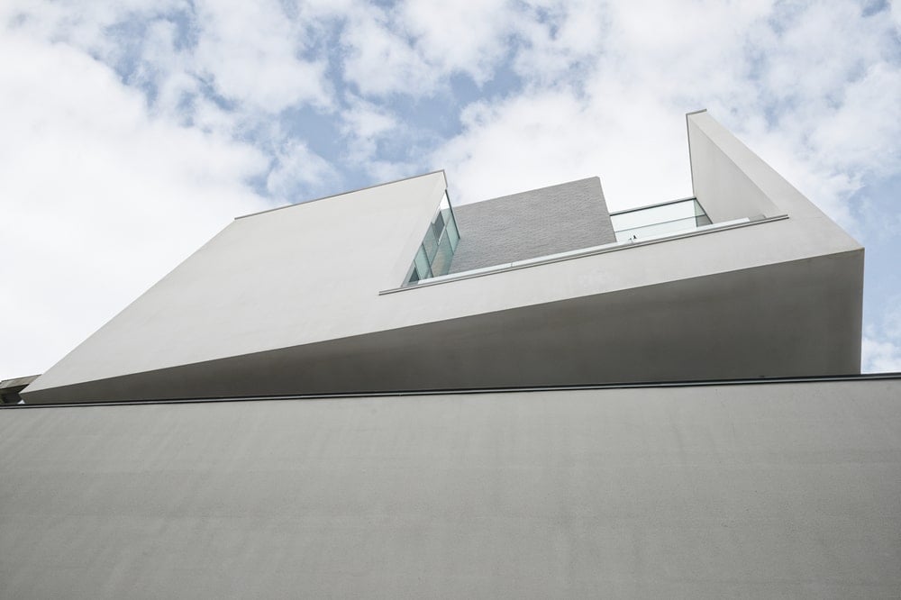 This is a look up at the askew design of the upper floor with bright concrete walls.