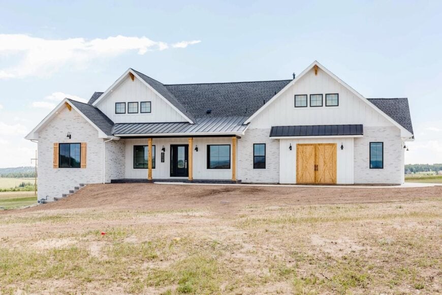 Front exterior view showing the board and batten siding, stone accents, and a covered porch lined with wooden posts.