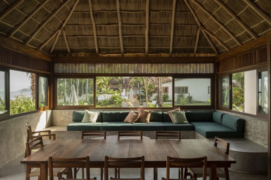 This is a closer look at the rectangular dining table and the living room area on the far side by the wide windows.