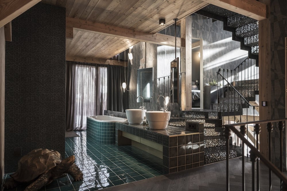 This is a view of the rustic bathroom with sea green tiles, freestanding sink and a large bathtub on the far side.