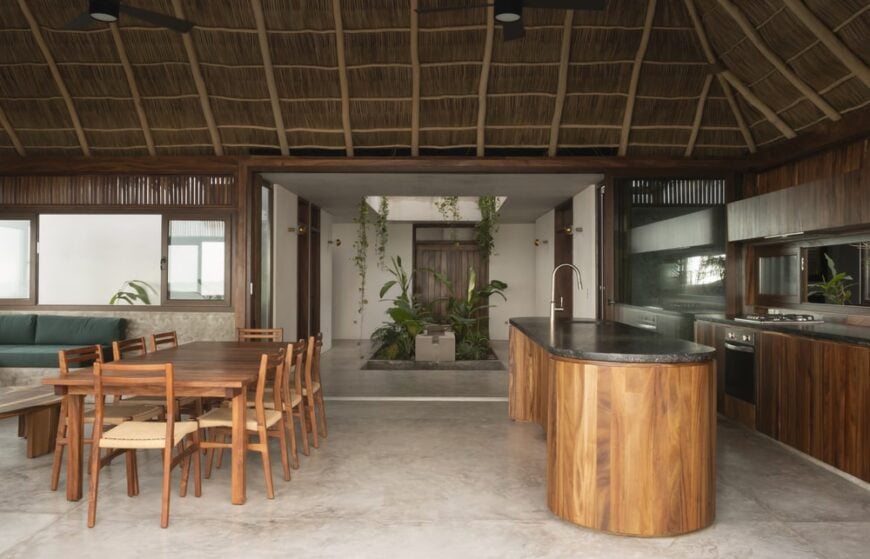 This is a closer view of the great room that houses the kitchen, dining and living room areas under a tall ceiling.