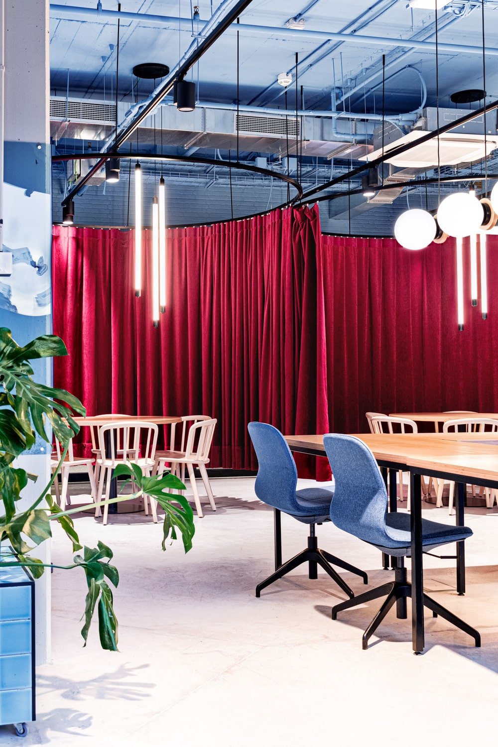 There are two curtained sections that has large round wooden tables paired with chairs and topped with lighting.
