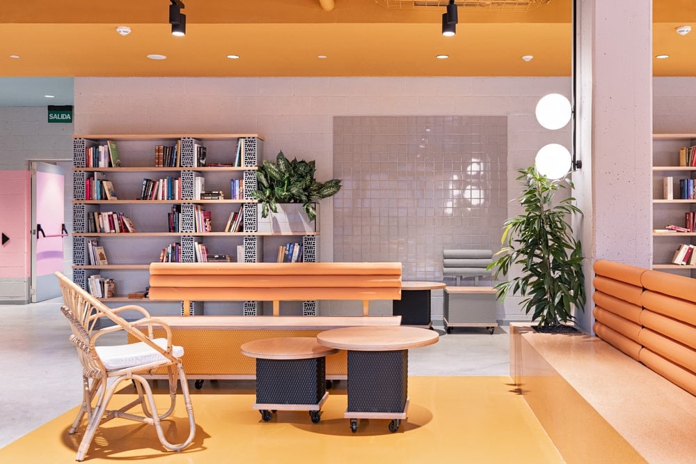 This is a look at the section of the sitting area with a built-in cushioned bench, a wooden chair and a couple of coffee tables complemented by the yellow tones and potted plants.