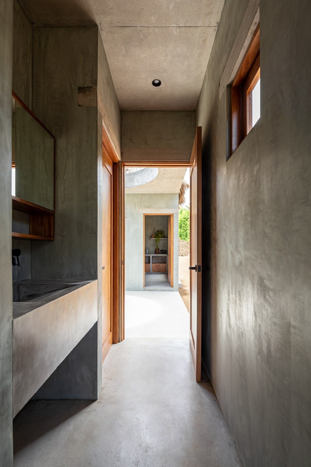 This is a close look at the vanity of the bathroom with a built-in concrete sink topped with a wall-mounted mirror.