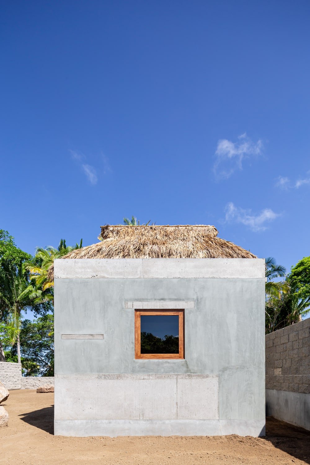 This is a look at the house's elevation that shows the concrete exterior walls and palm roof.
