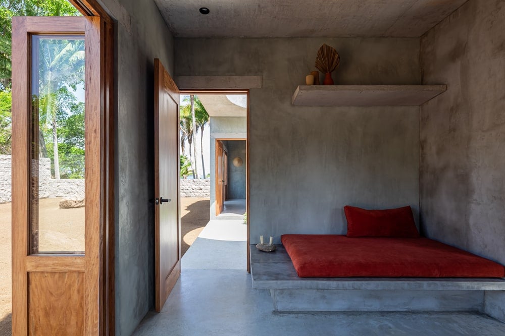 This is a look at the other bedroom that has a large concrete platform structure for the bed cushion and is topped with a floating shelf.