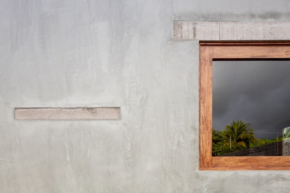 This is a close look at the concrete exterior wall and the wooden frame of the window that stands out.