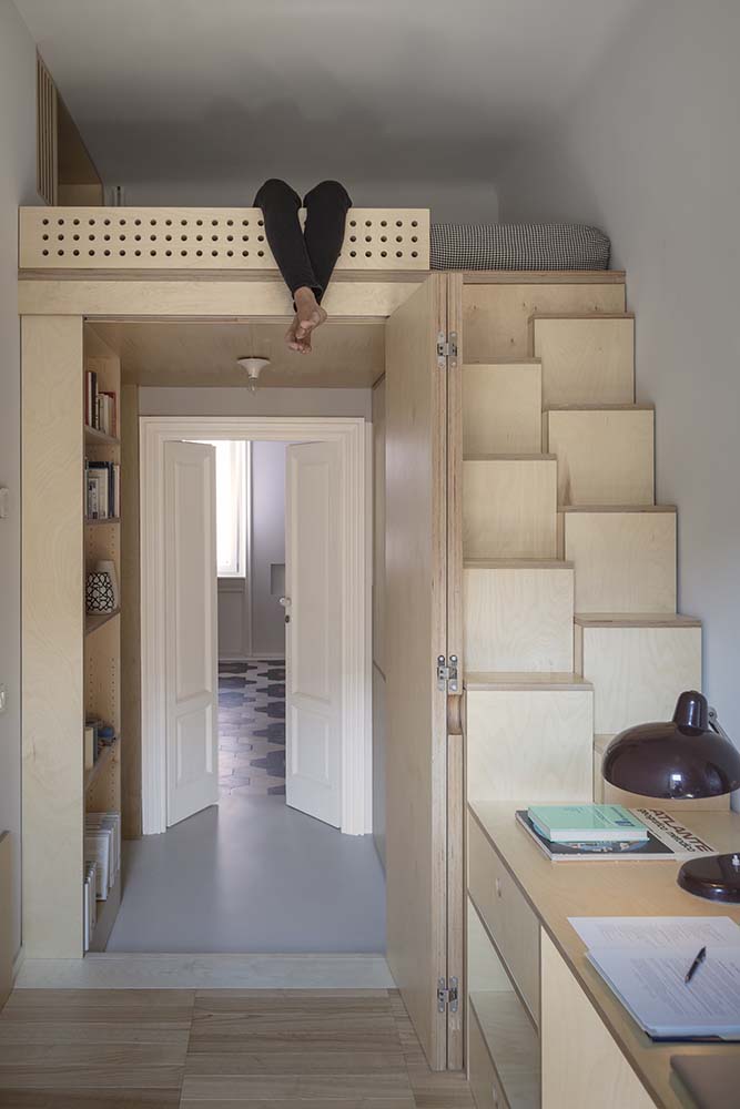 This is a close look at the loft-type bed that utilizes the vertical space above the entryway paired with a modern set of wooden steps.