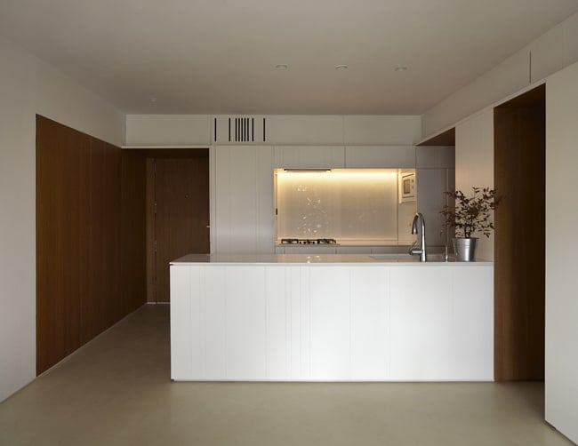 This is a full view of the kitchen that has a large white kitchen peninsula to match the modern white cabinetry of the cooking area.