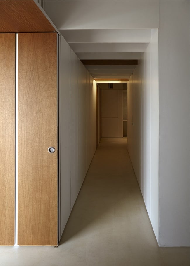 The set of wooden folding doors open to this long and narrow hallway with warm lighting.