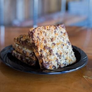 A plate of Hello Dolly Bars on a wooden table.