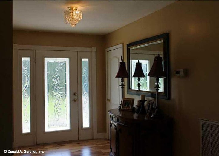 Foyer with a glazed entry door and a wooden console table topped with a framed mirror.