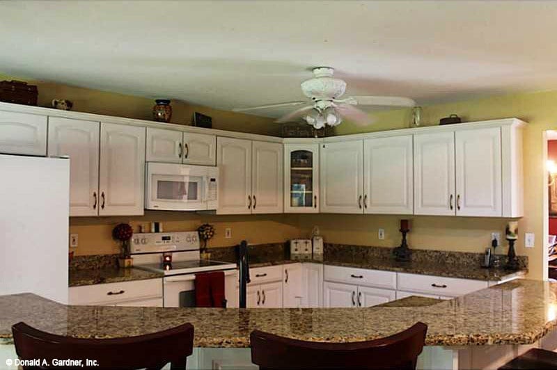 The kitchen offers white appliances, custom cabinetry, granite countertops, and a raised eating bar.