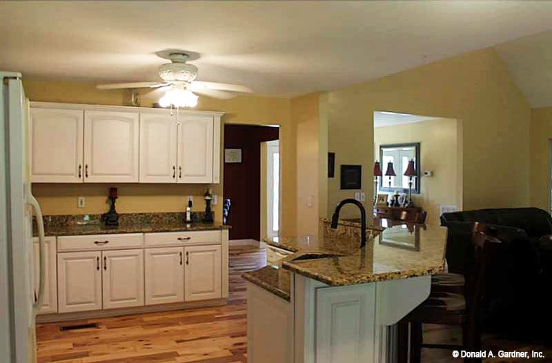 The granite top peninsula is fitted with a sink and a gooseneck faucet.