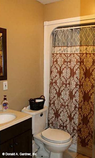The bathroom is equipped with a sink vanity, a toilet, and a tub and shower combo enclosed in a patterned curtain.The bathroom is equipped with a sink vanity, a toilet, and a tub and shower combo enclosed in a patterned curtain.