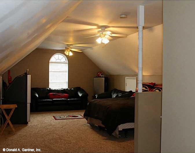 Bonus room with a leather sectional and a cozy bed over carpet flooring.