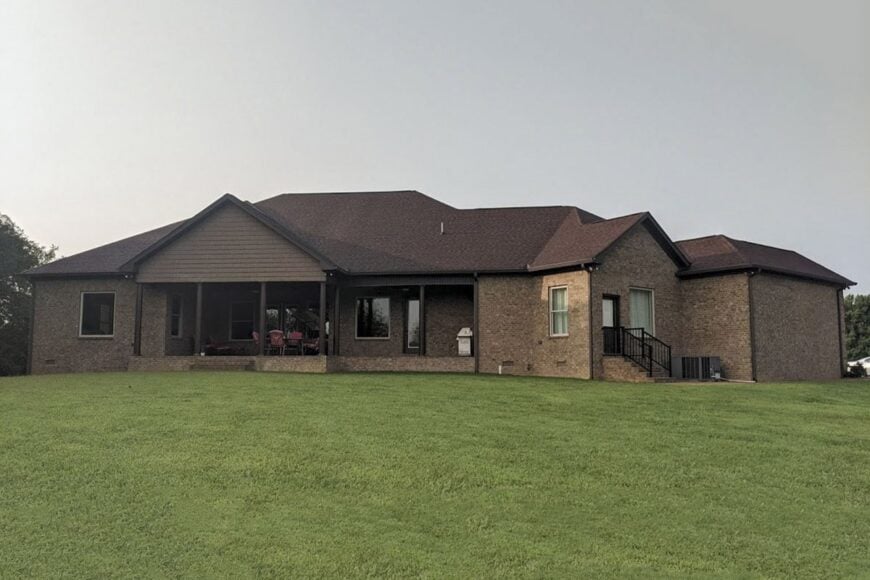 Rear exterior view with a wide covered porch framed with dark wood posts.