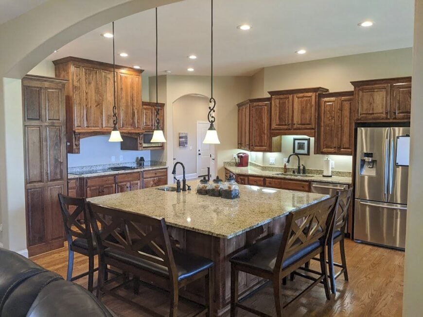 The kitchen offers natural wood cabinetry, stainless steel appliances, an immense center island.