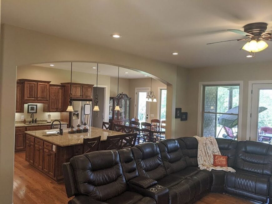 An open layout view showing the living room, kitchen, and dining area with an oversized archway serving as their divider.