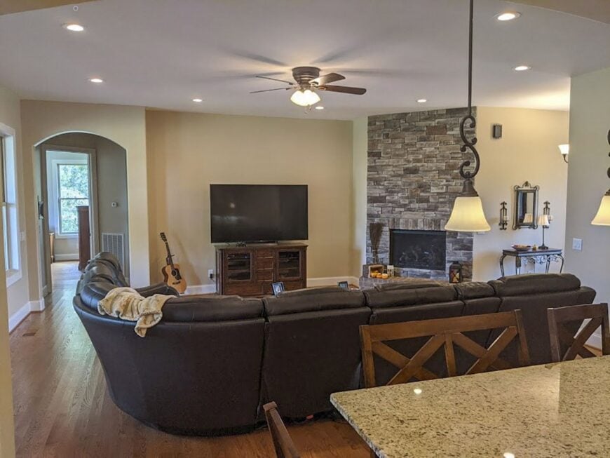 The living room includes a leather sectional, a TV, and a corner fireplace.