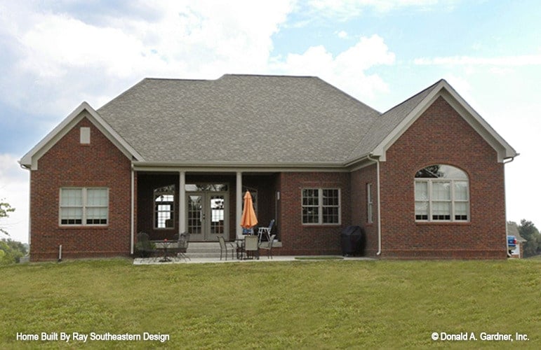 Rear exterior view with open patio and covered porch lined with gray pillars.