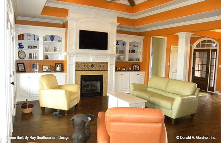 Living room with bright orange walls, multi-colored seats, a fireplace, and a stunning step ceiling.