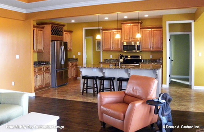 The living room opens to the kitchen defined by yellow walls.