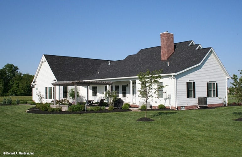 Rear exterior view showing the brick chimney, a wide covered porch, and pergola patio.